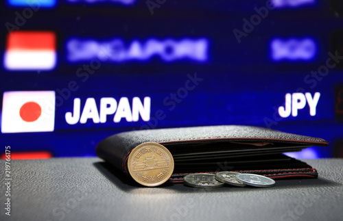 Japanese ten Yen coins on obverse (JPY) and pile of other Japanese coins on black floor with black wallet and digital board of currency exchange money background, the concept of finance. photo