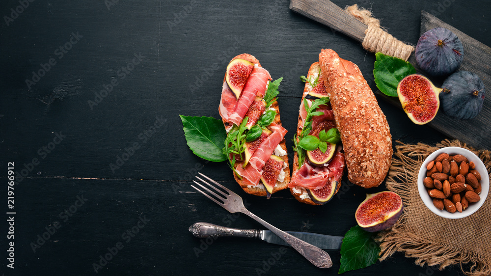 Bruschetta with prosciutto, fresh figs and cheese. On the old background. Healthy food. Free space for text. Top view. Bruschetta with prosciutto, fresh figs and cheese. On the old background. Healthy food. Free space for text. Top view.