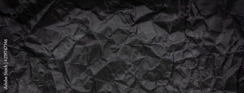 Ragged crumpled dark black paper texture background