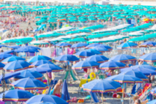Beach scene on a busy summer day with blurred out people, Beach full of people, tourists with umbrella in summer blurred image.