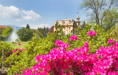 spring landscape with pink flowers and beautiful villa house with fountain in bright day blue sky background.