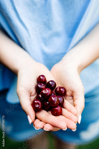 Woman holding cherries in her hands.