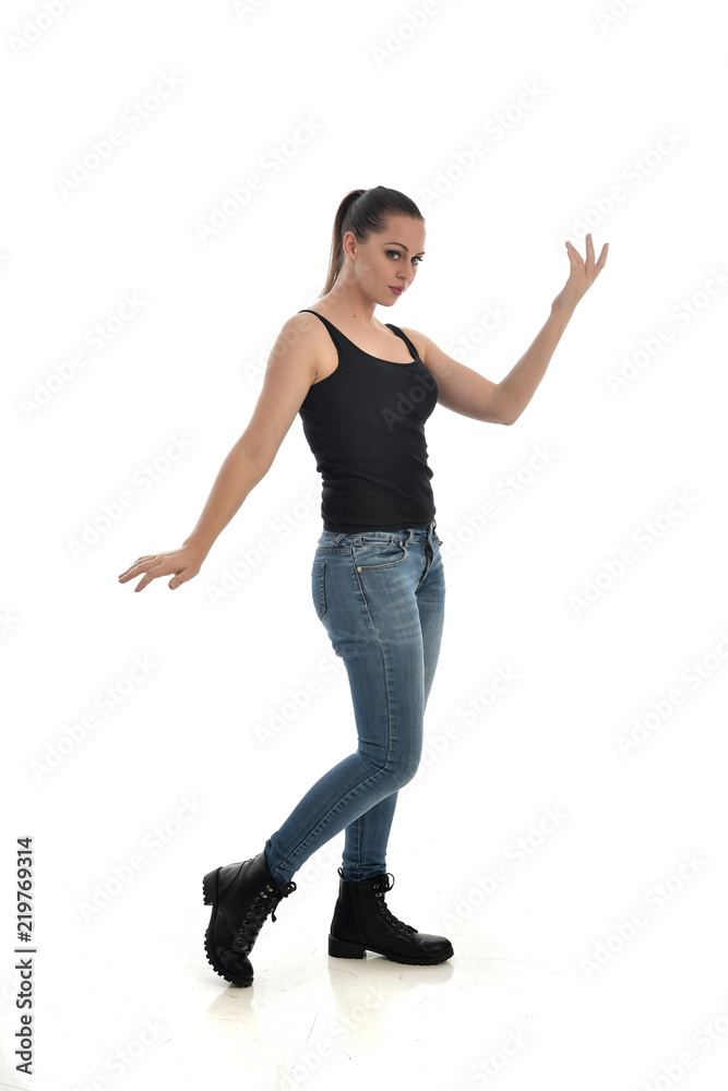 full length portrait of brunette girl wearing black single and jeans. standing pose facing the camera. isolated on white studio background. full length portrait of brunette girl wearing black single and jeans. standing pose facing the camera. isolated on white studio background.