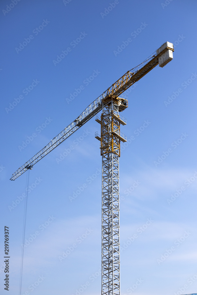 Construction of a business center using a tower crane. Construction site, tower crane, blue sky background.