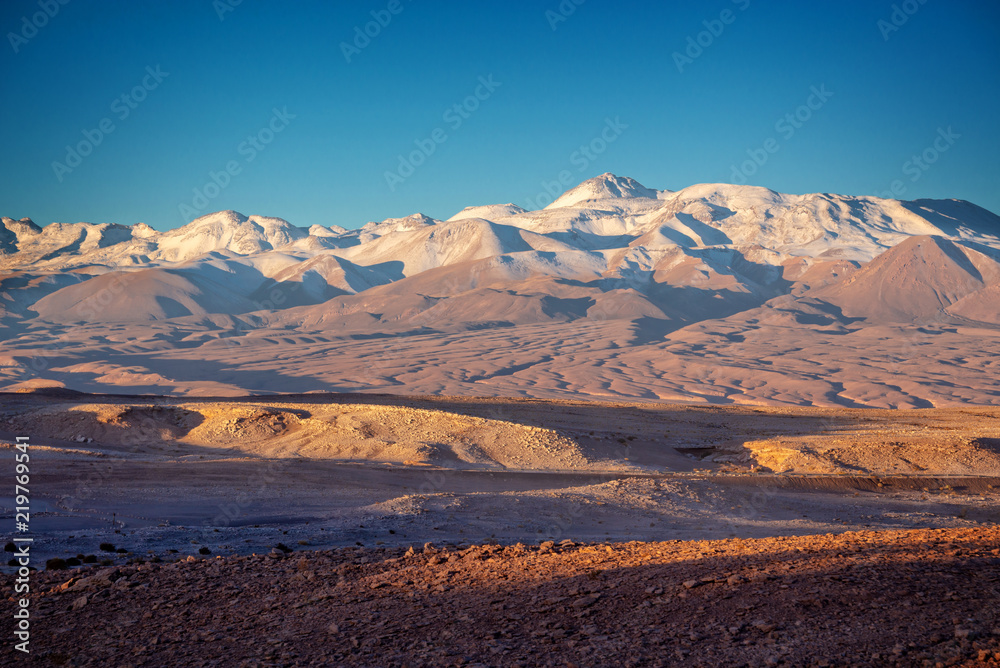 Moon Valley in Atacama desert at sunset, snowy Andes mountain range in the background, Chile