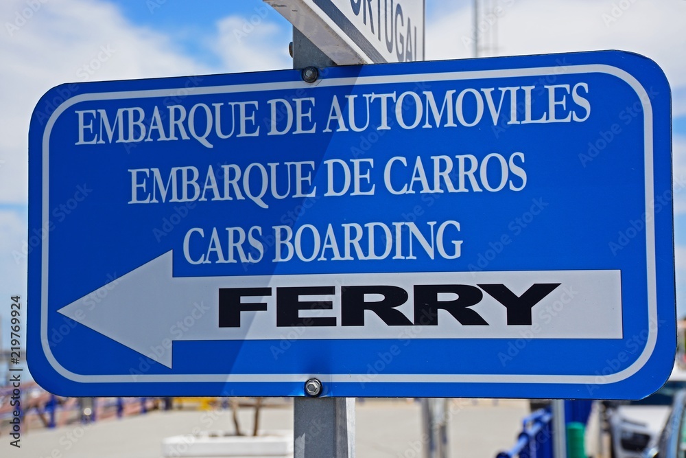 Blue and white cars boarding Ferry sign along the waterfront, Ayamonte, Spain.