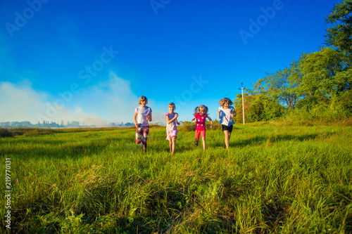 Group of happy kids running in green summer field