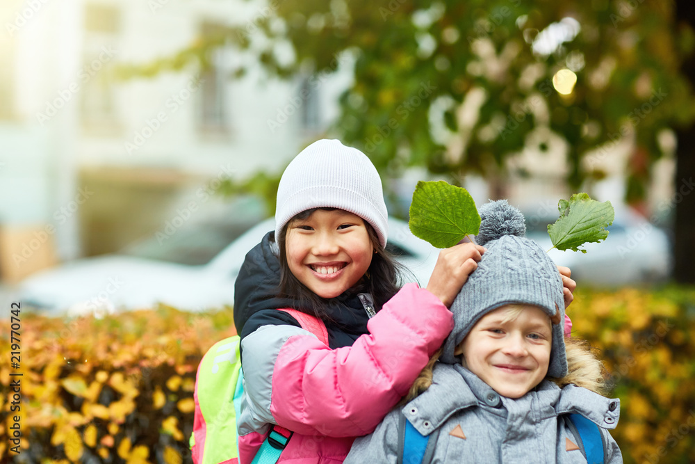 Cheerful girl having fun with her cute friend while holding two green leaves over his head Cheerful girl having fun with her cute friend while holding two green leaves over his head