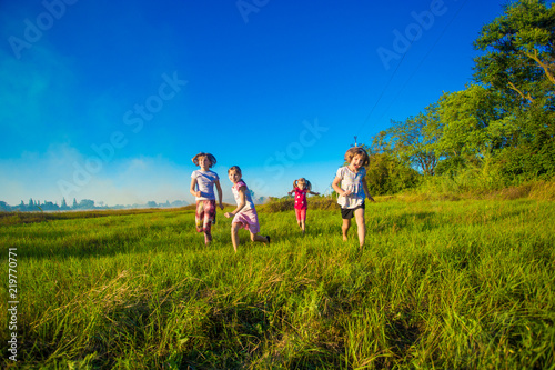 Group of happy kids running in green summer field