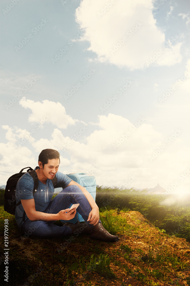 Young asian traveler sitting while using his phone
