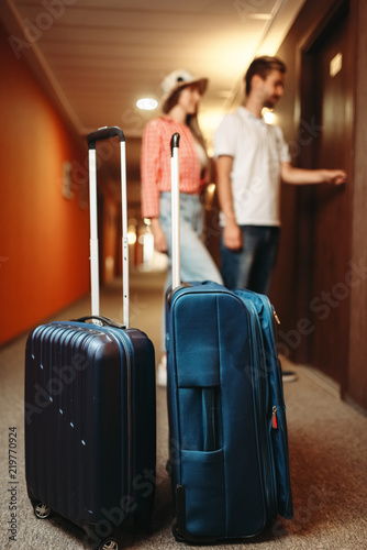 Suitcases in hotel hallway, couple open the door