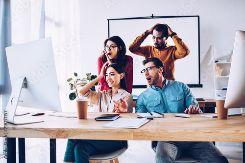 shocked multiracial business team working on project together in office