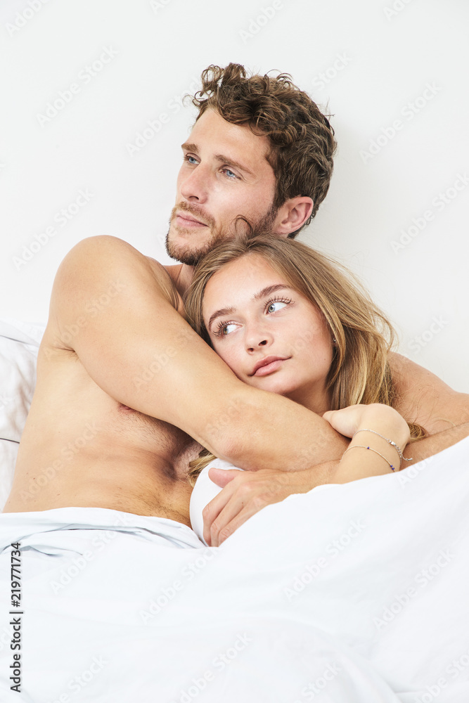 Young couple relaxing in bed, looking away Young couple relaxing in bed, looking away
