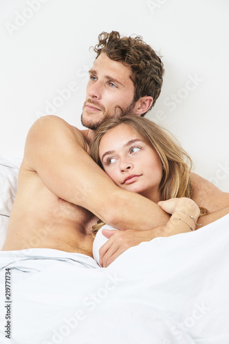 Young couple relaxing in bed, looking away