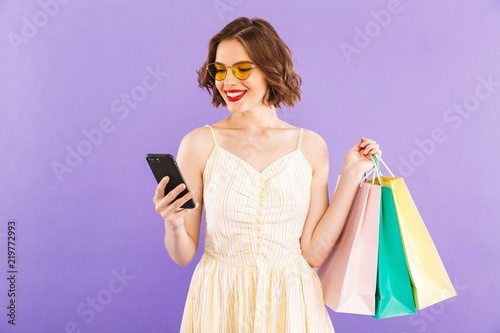 Young woman using mobile phone isolated over purple wall background.