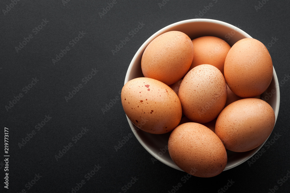 brown eggs in bowl isolated on dark background. top view brown eggs in bowl isolated on dark background. top view