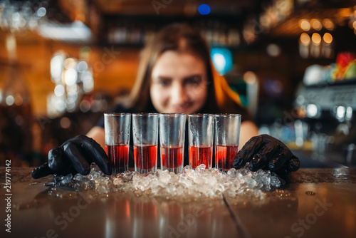 Photography Female barman in gloves puts drinks on ice