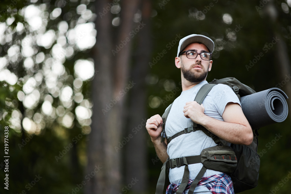 Obraz premium Young man wearing eyeglasses in backpack travelling through the forest
