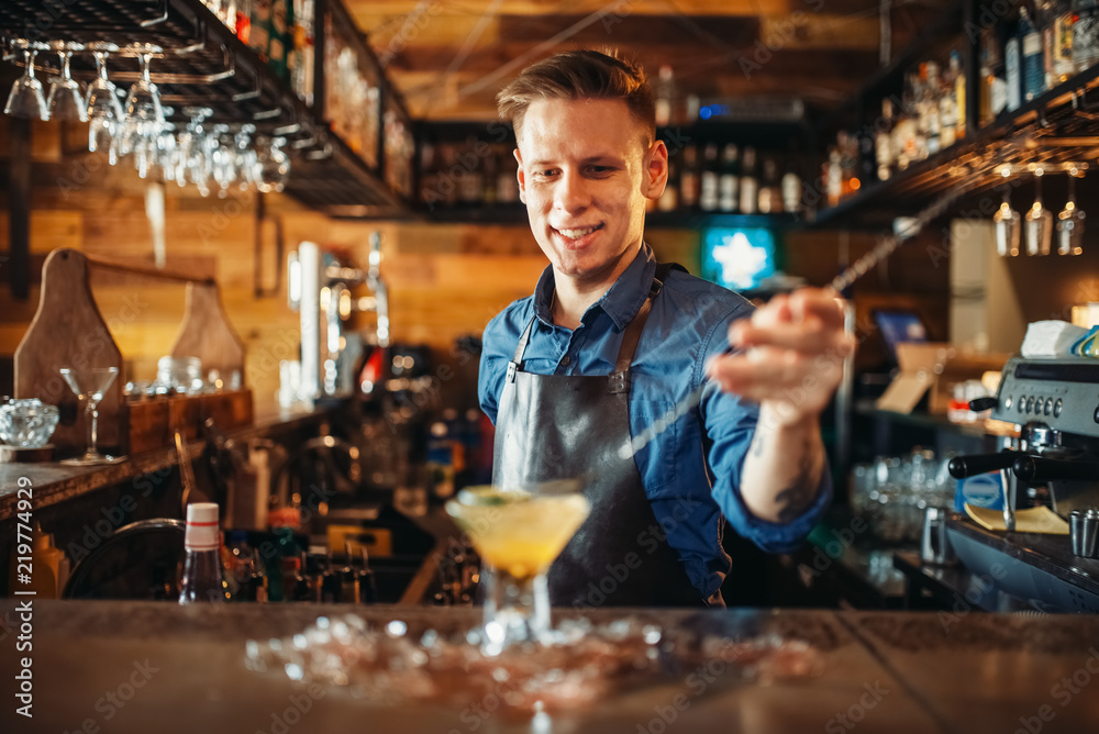 Male bartender prepares alcoholic coctail with ice