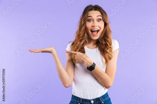 Emotional woman standing isolated over purple wall background pointing.