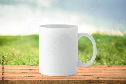 White mug on empty wooden table. Morning background concept. © Lemonsoup14