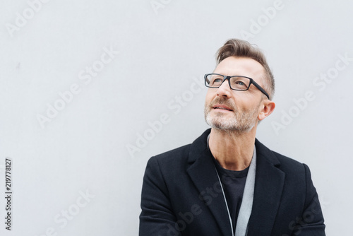 Man with glasses wearing black coat looking up © contrastwerkstatt