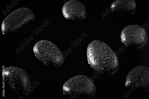 Close up of water drops at black stones on black water background