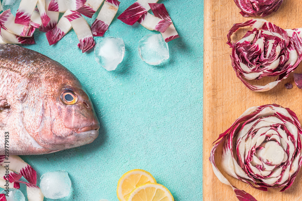 Head of raw fish with cooking ingredients on light blue kitchen table background, top view, flat lay. Seafood concept with copy space