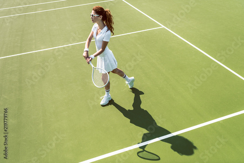 side view of young attractive woman in white tennis uniform playing tennis on court © LIGHTFIELD STUDIOS