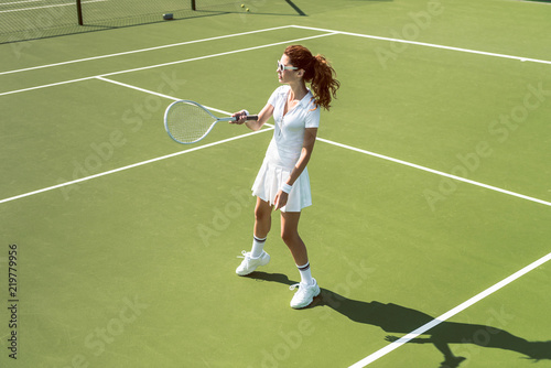 young female tennis player in sunglasses playing tennis on court