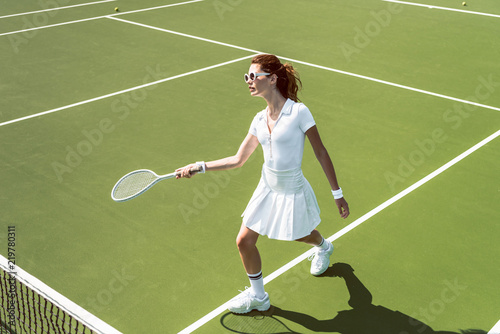 beautiful woman on white sportswear and sunglasses playing tennis on court