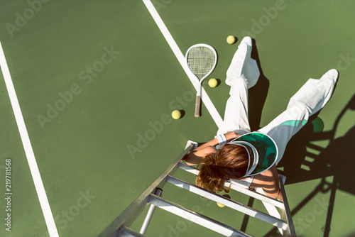 overhead view of woman in stylish white clothing and cap posing on referee chair on tennis court © LIGHTFIELD STUDIOS