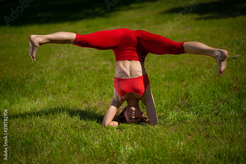 Young attractive woman practicing yoga outdoors. The girl performs a handstand upside down