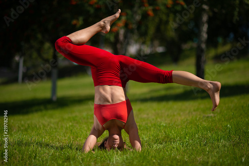 Young attractive woman practicing yoga outdoors. The girl performs a handstand upside down