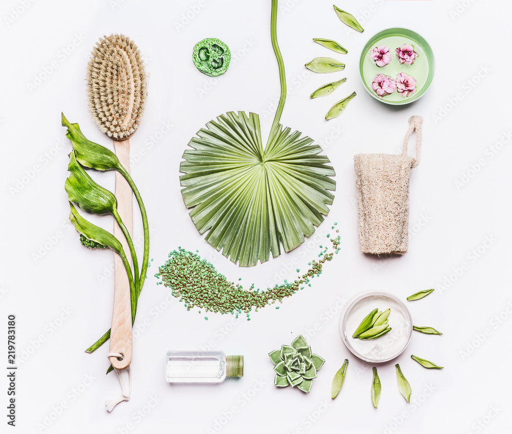 Various brushes and natural products for cellulite treatment at home on  white background. Spa setting flat lay with tropical leaves and flowers.  Massage tools. Beauty and body care concept, top view Stock