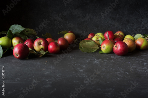 Apples with leaves on black stone plate