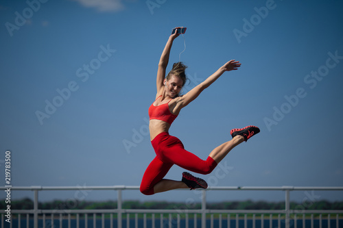 Young caucasian girl performs twine jumping on sky backround.