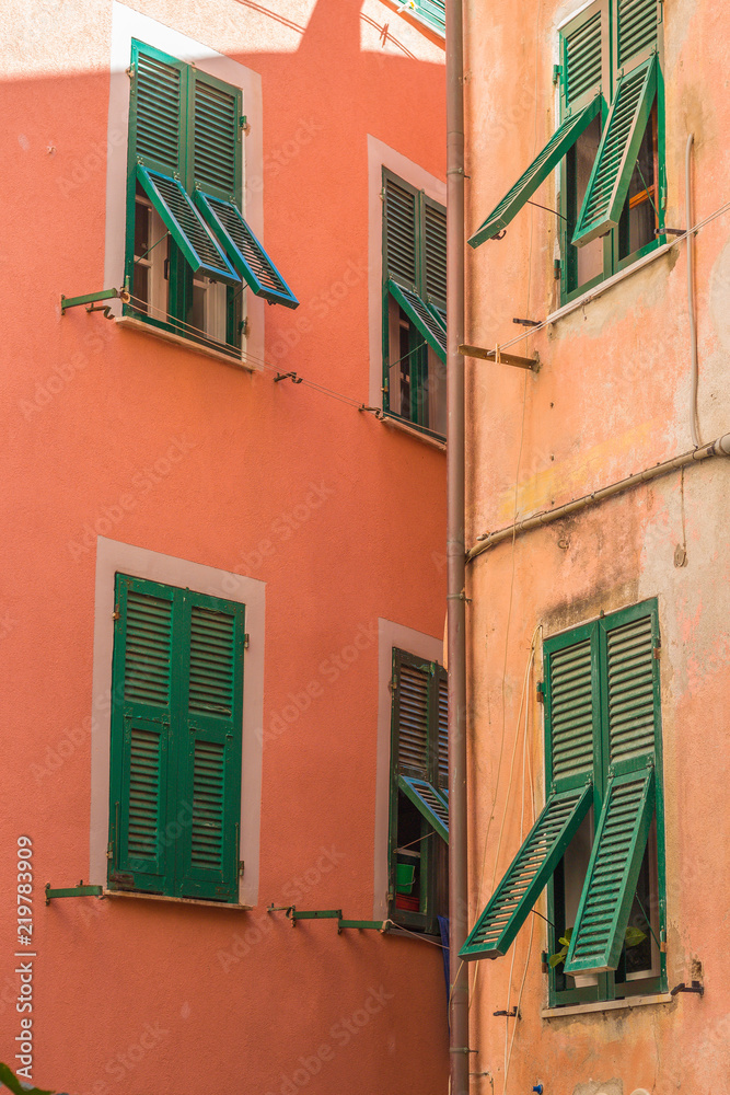 Two colorful buildings very close together in the small village of Vernazza, Italy, in the Cinque Terre region.  Densely packed homes seem to be on top of each other. 