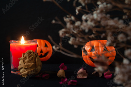 Orange pumpkin as a head with carved eyes and a smile with burning candles on a black background, Halloween home decoration