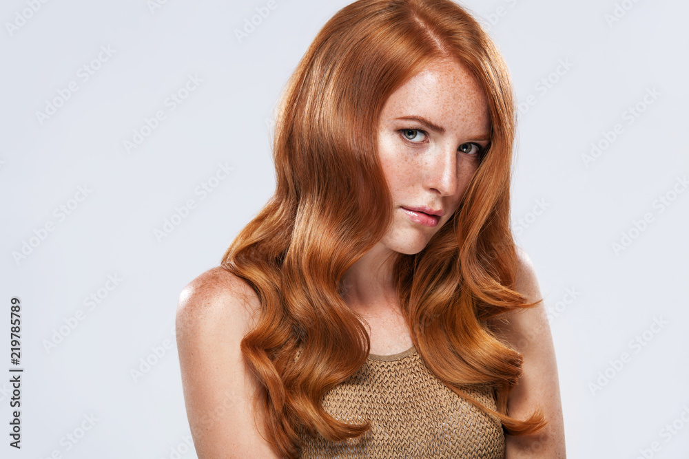 Naklejka premium Red head girl with long and shiny wavy hair. Beauty. Beautiful model woman with curly ginger hairstyle and frackles.
