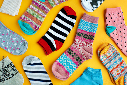 Multi-colored socks on a bright background. View from above. Striped, blue, pink, patterned socks for autumn and winter. Warm clothes in the form of socks on a yellow background.
