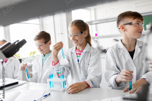 education, science and children concept - kids with test tubes studying chemistry at school laboratory