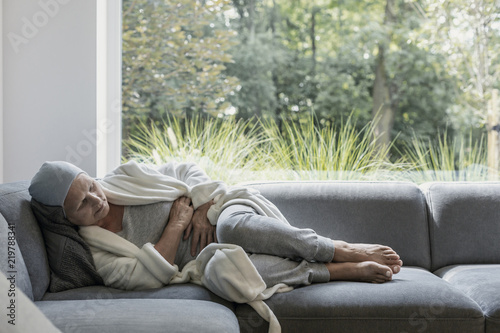 Tableau sur toile Weak elderly woman with cancer and stomach pain alone at home