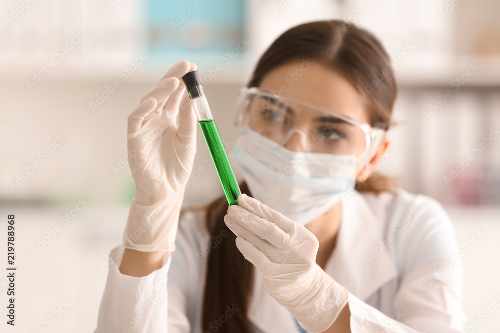 Female scientist holding test tube with color sample in laboratory Female scientist holding test tube with color sample in laboratory