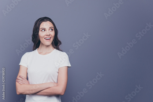 Attractive pretty adorable wondered stylish curly-haired girl in white t-shirt, folded arms, isolated over grey background, copy space
