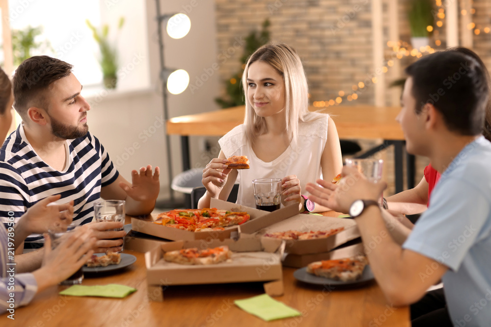 Young people eating pizza at table