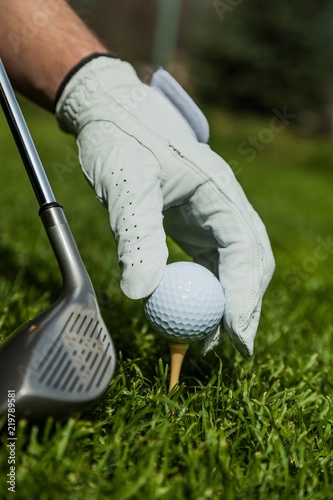 Hand with Glove Placing Golf Ball on a Tee