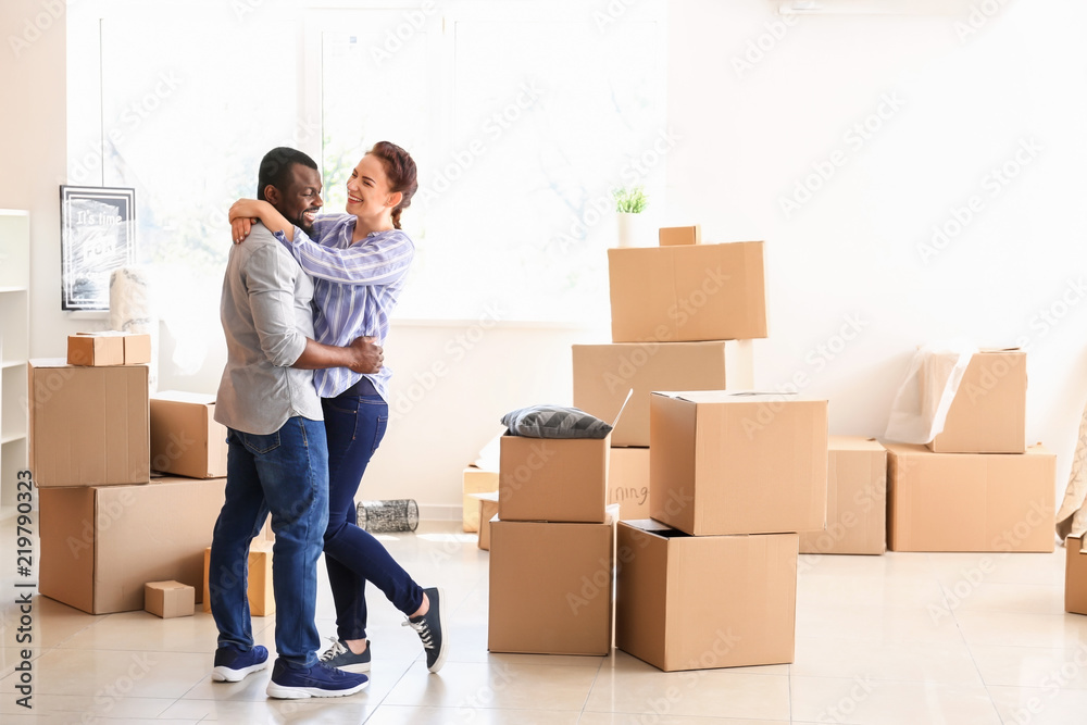 Interracial couple with carton boxes in room. Moving into new house Interracial couple with carton boxes in room. Moving into new house