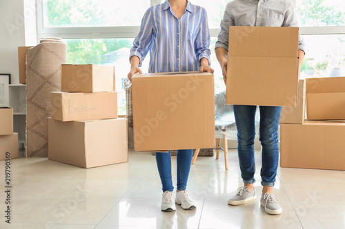 Young couple with boxes indoors. Moving into new house © Pixel-Shot