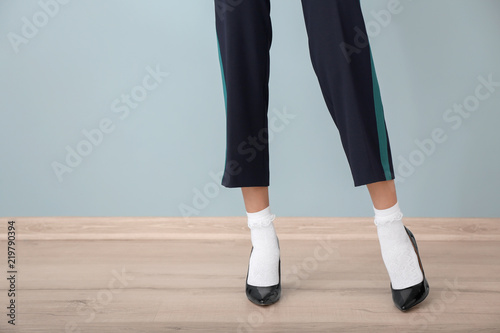 Legs of beautiful young woman standing against color wall